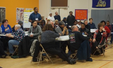 Groups of people sitting at tables watching a presentation