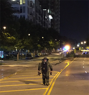 personnel in bomb squad suit walking down street